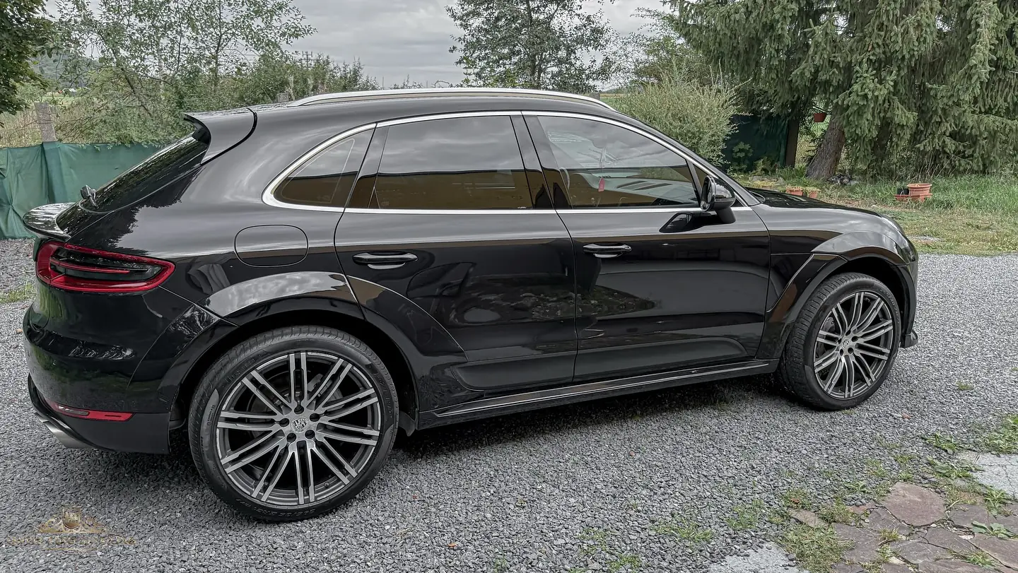 Čierne Porsche Macan z boku zozadu, vyleštený lak a veľké disky na štrku