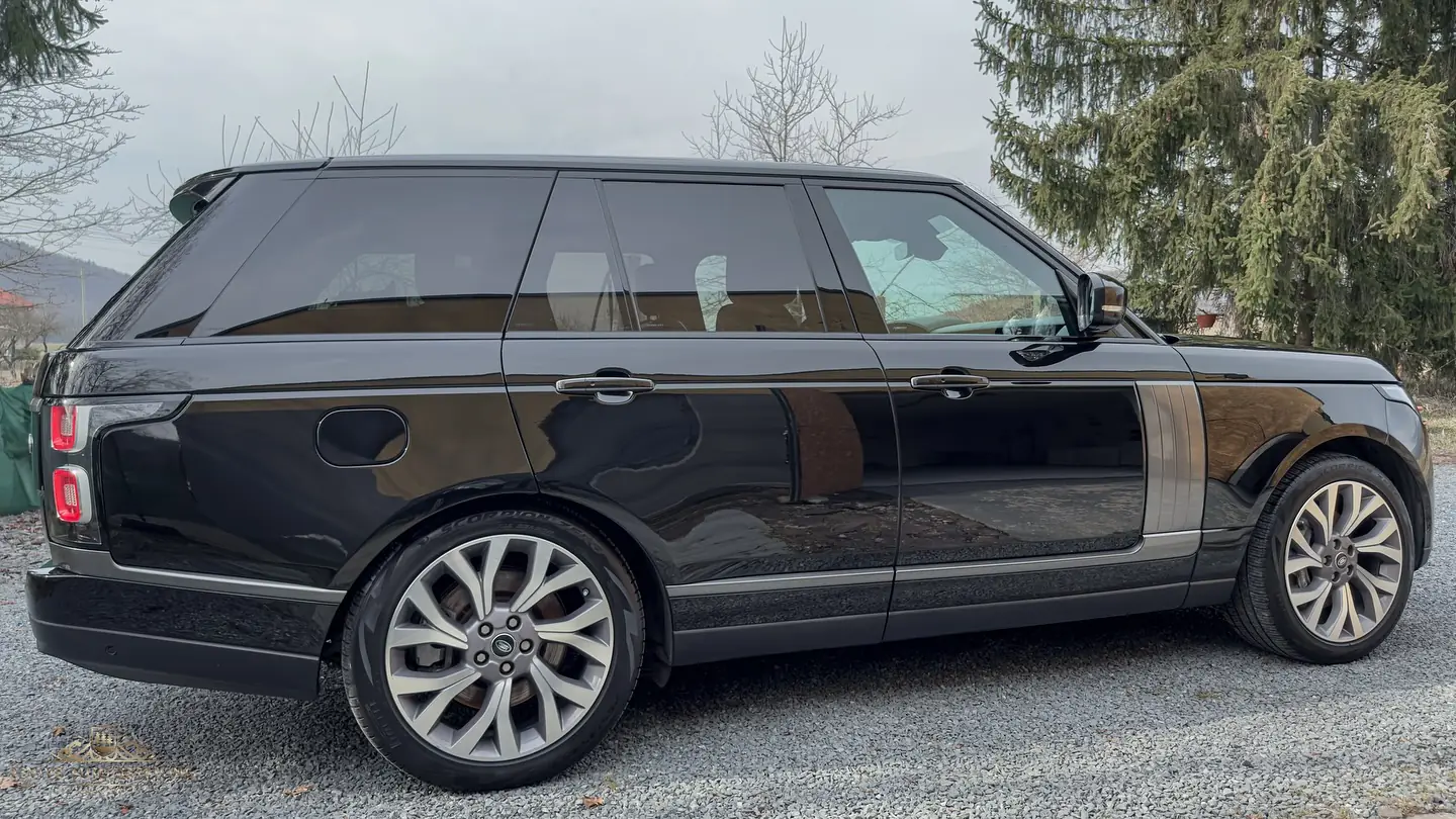 Čierny Range Rover Autobiography z boku po leštení, v laku sa zrkadlí štrk a stromy