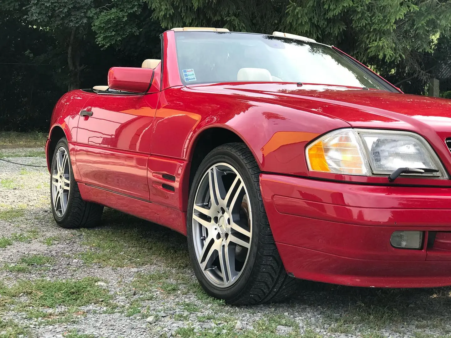 Červený kabriolet Mercedes SL500 so stiahnutou strechou, vyleštený blatník, koleso a svetlomet